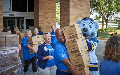 Employees and St. Louis Blue's Louie load diapers to deliver to the St. Louis Area Diaper Bank